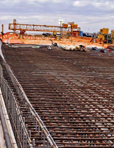 Construction worker overseeing the progress on a bridge reinforcing steel structure.